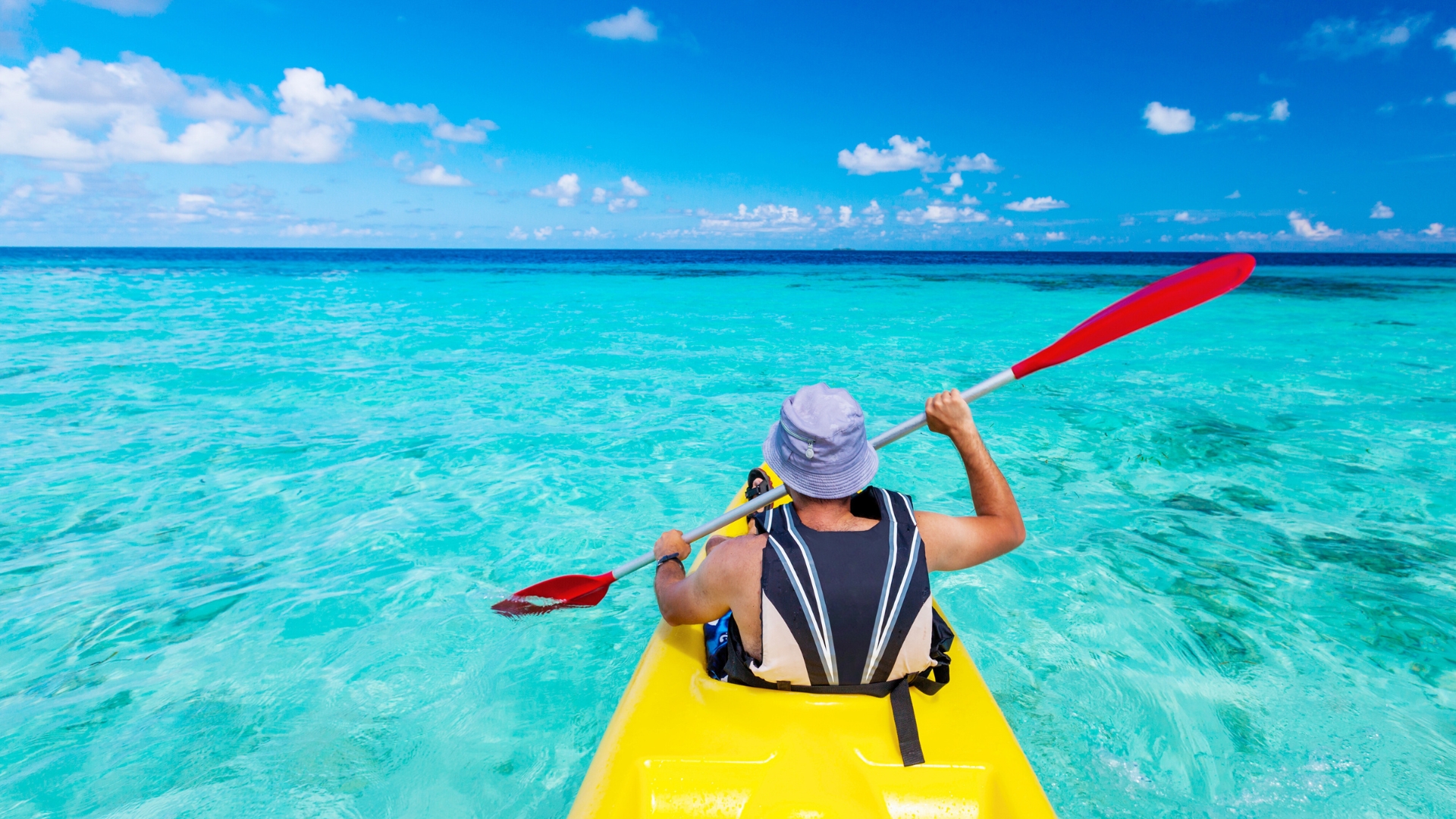 Young caucasian man kayaking in sea at Maldives